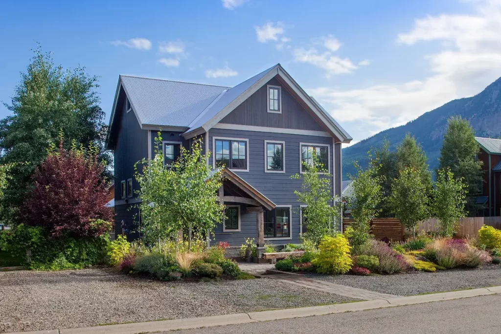 Modern home exterior surrounded by layered landscape planting and Crested Butte mountain views.