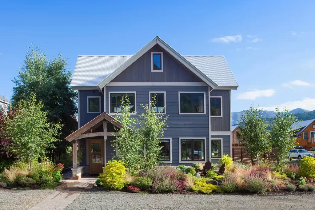 Symmetrical gabled front elevation with mountain-modern siding and a lush landscape in Crested Butte.