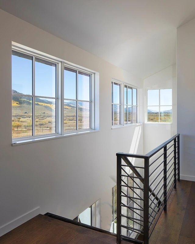 Upper-level hallway with large corner windows framing mountain views and natural light.
