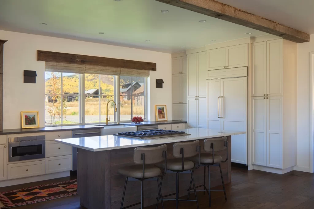 Spacious Colorado kitchen with a dark island, marble countertops, and mountain views through oversized windows.