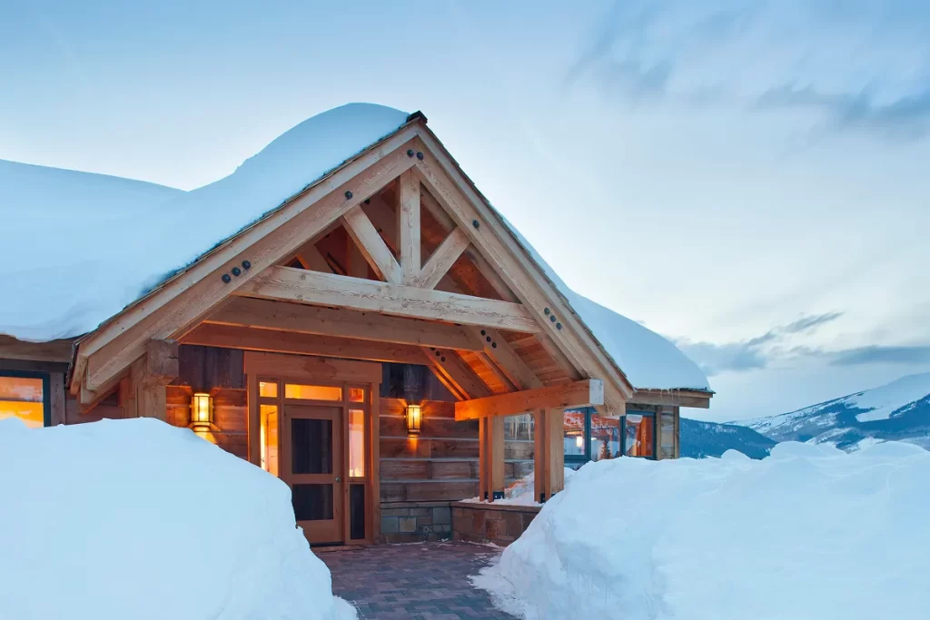Rustic front entry of mountain home in Crested Butte framed by timber beams and deep winter snowbanks.