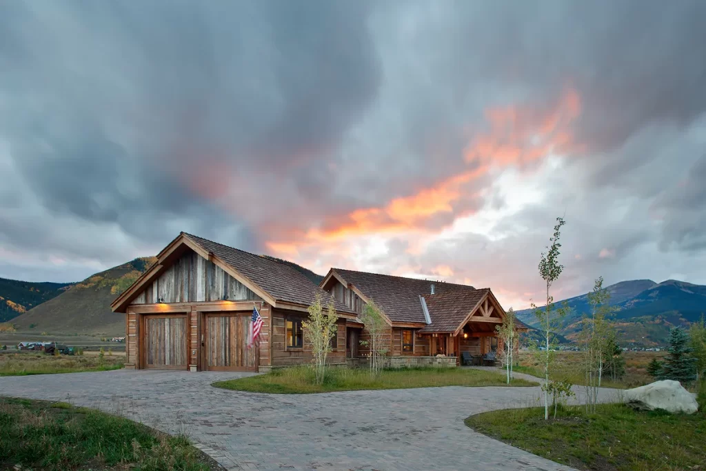 Mountain home with rustic garage and timber porch entry, set against a dramatic Crested Butte sunset sky.