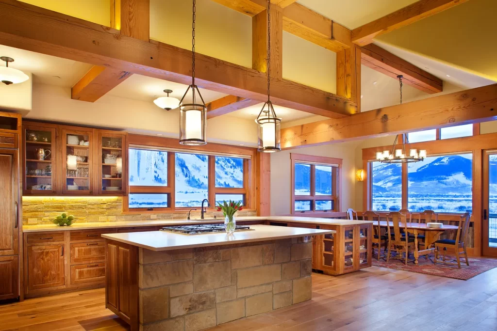 Open kitchen and great room with timber trusses and panoramic winter views of the Slate River valley.