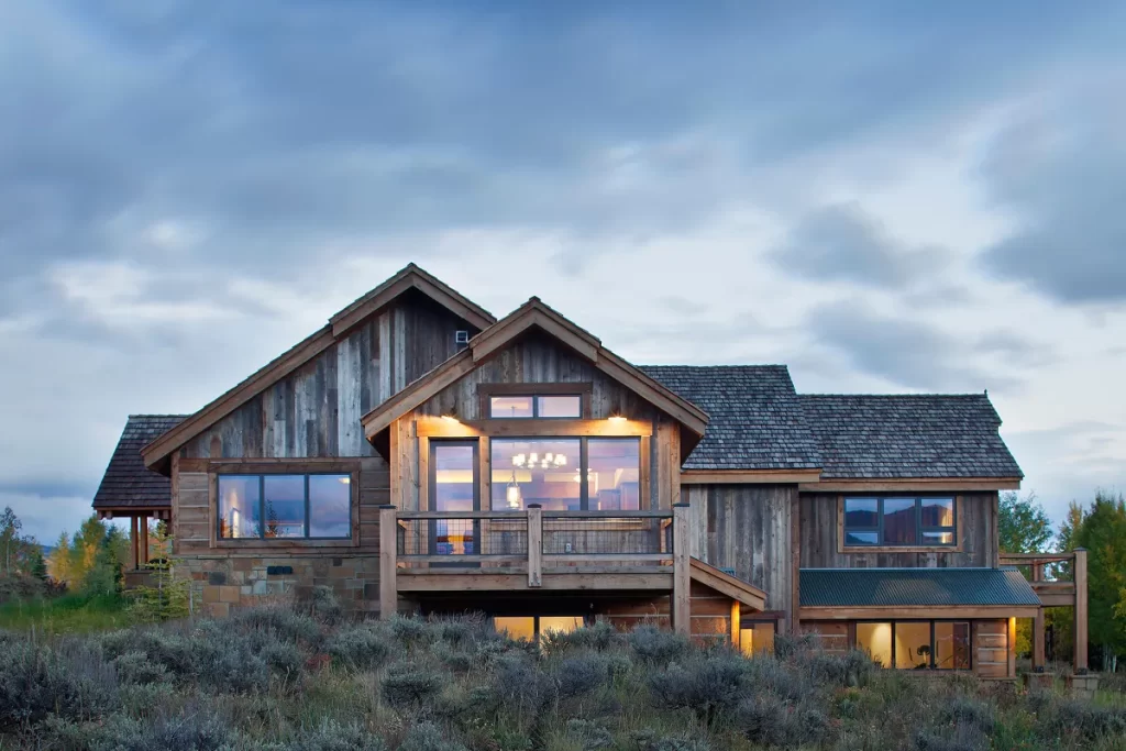 river_respite_crested_butte_exterior_rustic_reclaimed_wood_architecture Rustic reclaimed wood home exterior in Crested Butte with soft evening lighting and custom gable rooflines.